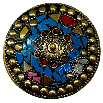 Decorative button with mosaic design and gold accents with areal top view on a white background